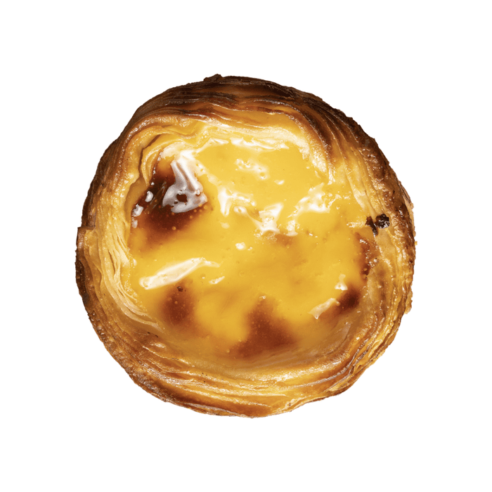 An aerial photo of an egg custard pastry from Portugal. This is a top down view of a Pastel de Nata on a white background. The Portuguese tart is circular and has a flaky puff pastry crust around the edges that is golden brown in color. In the middle is a yellow egg custard that has been browned and caramelized in the oven. 